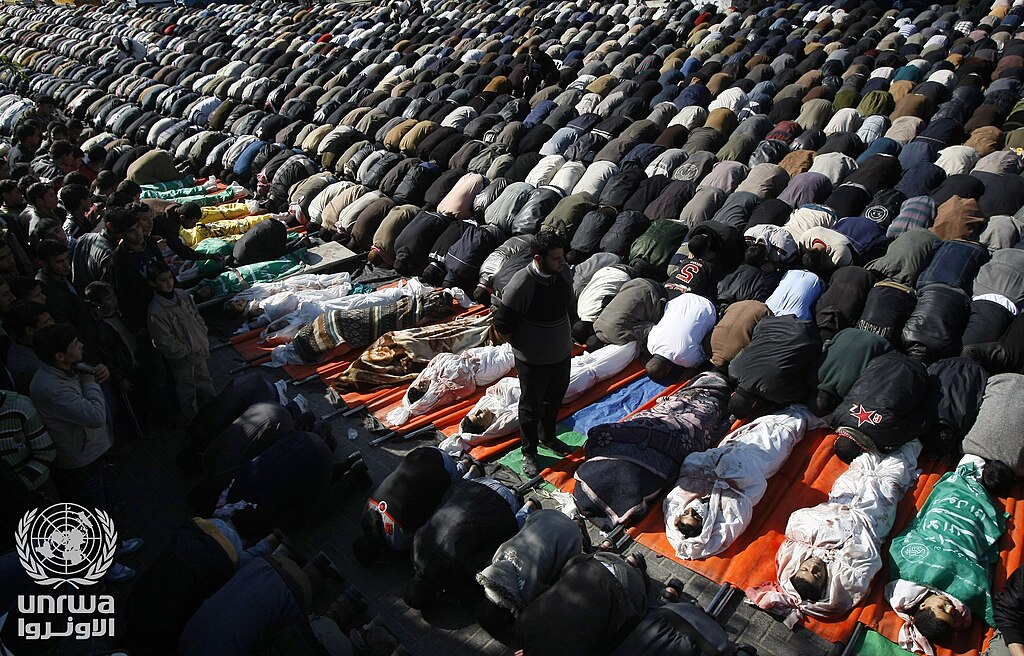 Palestinian mourners pray on January 7, 2009 near the bodies of 43 victims from an Israeli strike on a UN school